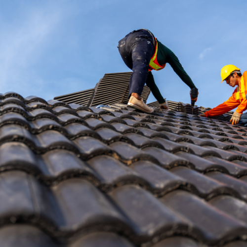 Roofing professional inspecting damaged roof tiles requiring maintenance