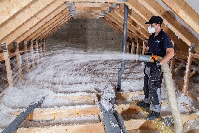 Profesional aplicando aislamiento térmico en un ático para mejorar la eficiencia energética del hogar